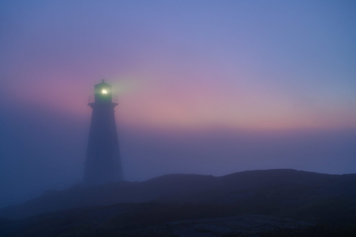 Cape Spear Lighthouse, St. John's, Newfoundland, Canada, in the fog with dawn glow in the sky.