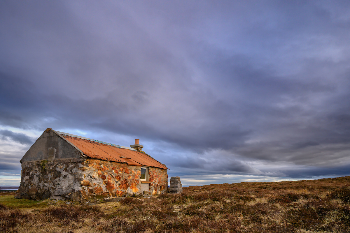 A shieling hut on the moorland under a stormy sky